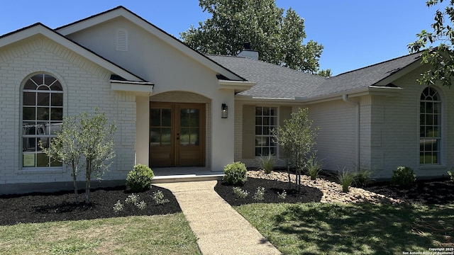 7335 Scintilla Ln, Boerne, TX 78015 - view of exterior entry with brick siding, roof with shingles, a chimney, and a lawn