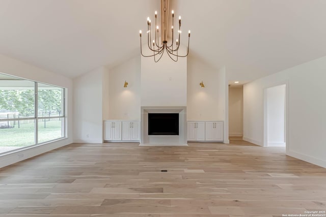 7335 Scintilla Ln, Boerne, TX 78015 - unfurnished living room featuring light wood-style flooring, baseboards, high vaulted ceiling, and a chandelier