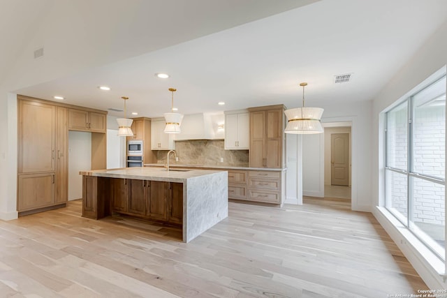 7335 Scintilla Ln, Boerne, TX 78015 - kitchen with light wood-style flooring, a sink, decorative backsplash, recessed lighting, and a spacious island