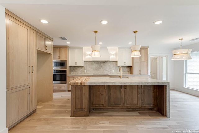 7335 Scintilla Ln, Boerne, TX 78015 - kitchen with appliances with stainless steel finishes, a sink, custom range hood, light wood-style flooring, and light countertops