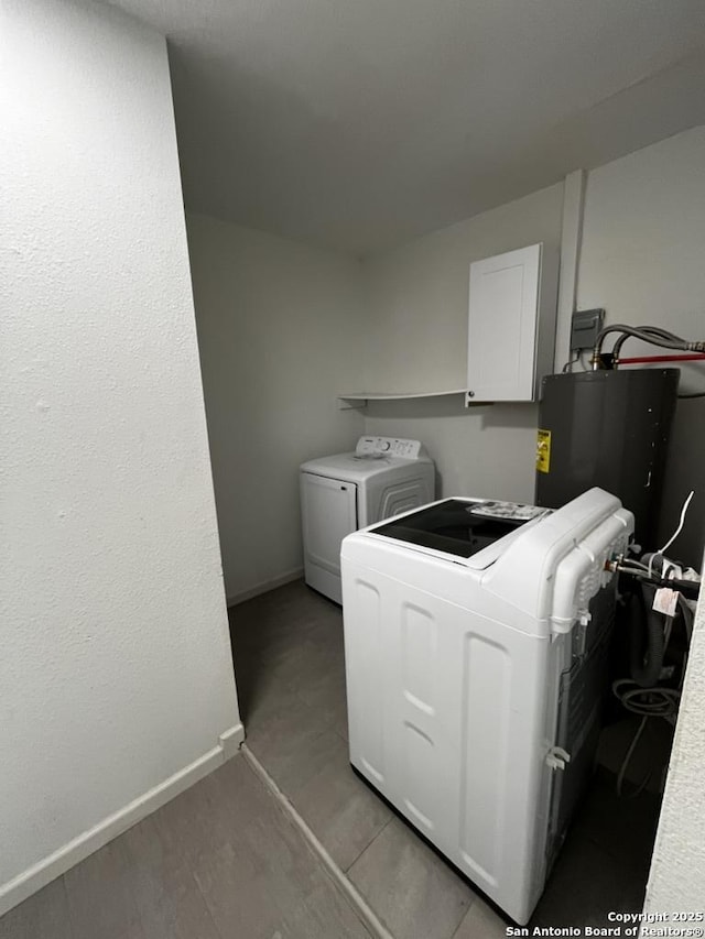clothes washing area with separate washer and dryer and baseboards