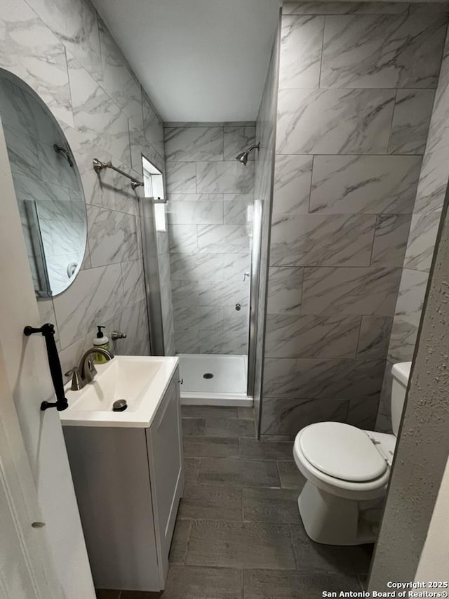 full bath with toilet, a stall shower, tile walls, and vanity