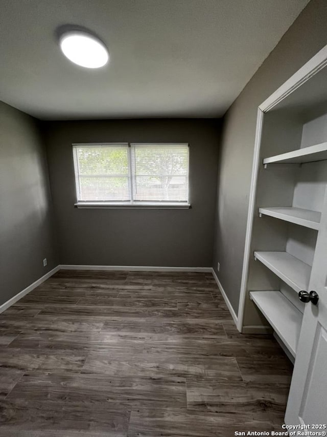 spare room with dark wood-style flooring and baseboards