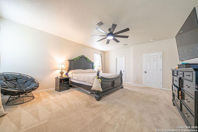 bedroom featuring light carpet, baseboards, a textured ceiling, and a ceiling fan