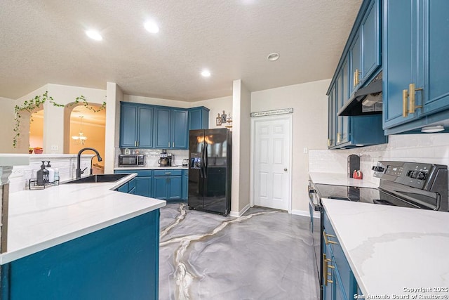 kitchen featuring black fridge, electric range oven, blue cabinetry, under cabinet range hood, and recessed lighting