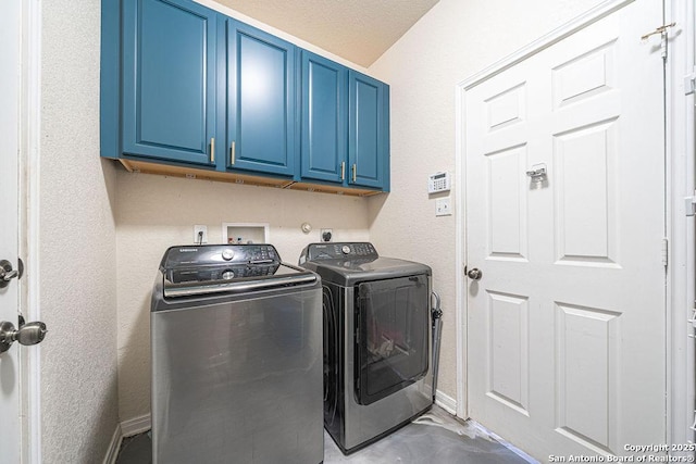 washroom with cabinet space, washing machine and dryer, and baseboards