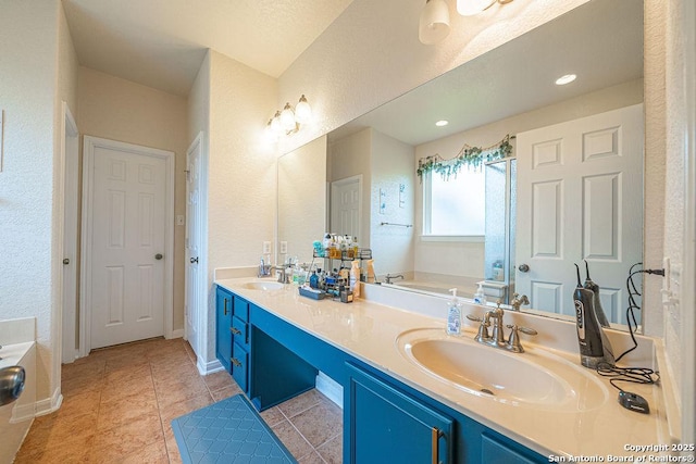bathroom featuring a garden tub, double vanity, a textured wall, baseboards, and tile patterned flooring