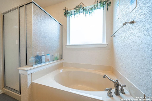 full bathroom featuring a garden tub, a shower stall, and a textured wall