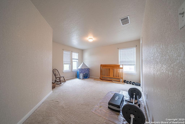 carpeted spare room featuring baseboards, a textured ceiling, and a textured wall