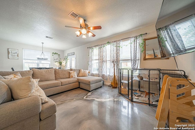 living area with concrete floors, a textured ceiling, ceiling fan, and a chandelier