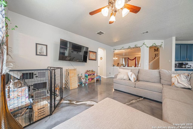 living room featuring concrete floors, arched walkways, a ceiling fan, baseboards, and a textured ceiling