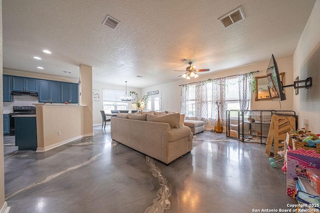 living area with finished concrete floors, ceiling fan, a textured ceiling, a chandelier, and recessed lighting