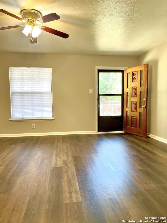 unfurnished living room featuring dark wood finished floors, a ceiling fan, baseboards, and a textured ceiling