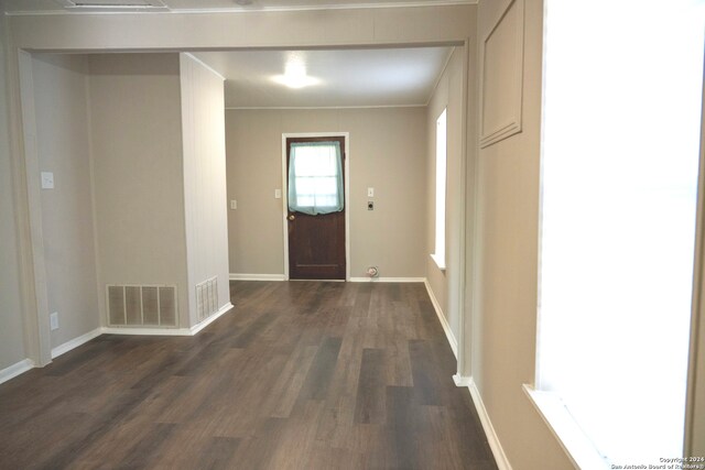 doorway with dark wood-style flooring, crown molding, and baseboards