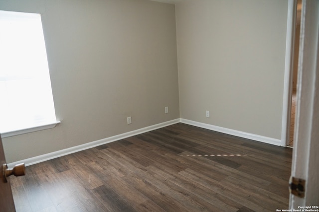 spare room with baseboards and dark wood finished floors