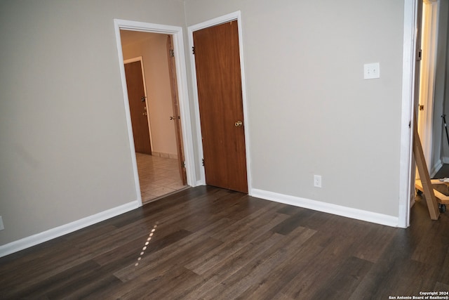 unfurnished bedroom featuring dark wood-type flooring and baseboards