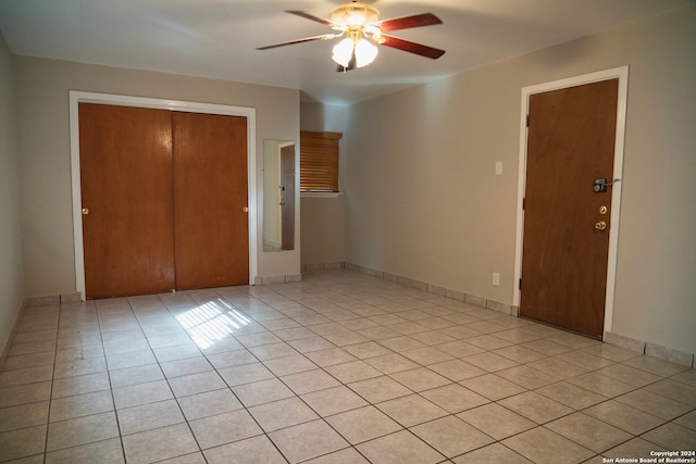 unfurnished bedroom with a closet, light tile patterned flooring, ceiling fan, and baseboards