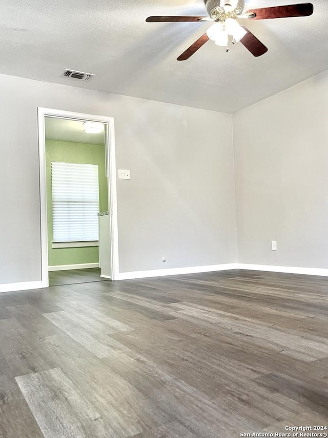 empty room with wood finished floors, a ceiling fan, and baseboards