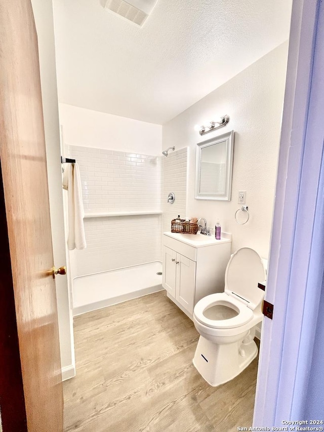 bathroom with a shower, wood finished floors, vanity, toilet, and a textured ceiling