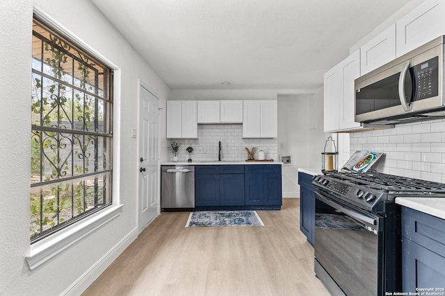 3327 K, San Antonio, TX 78220 - kitchen featuring appliances with stainless steel finishes, a sink, blue cabinetry, and light wood finished floors