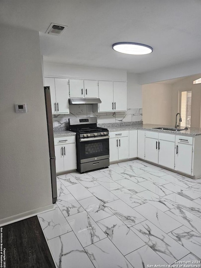 kitchen featuring stainless steel appliances, a sink, under cabinet range hood, white cabinetry, and light marble finish floors