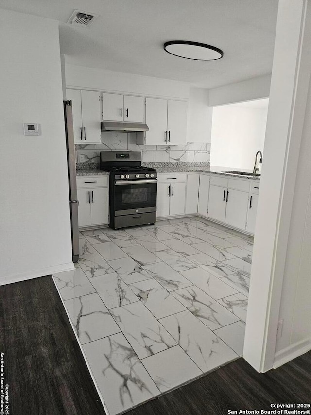 kitchen with stainless steel appliances, under cabinet range hood, a sink, and white cabinets