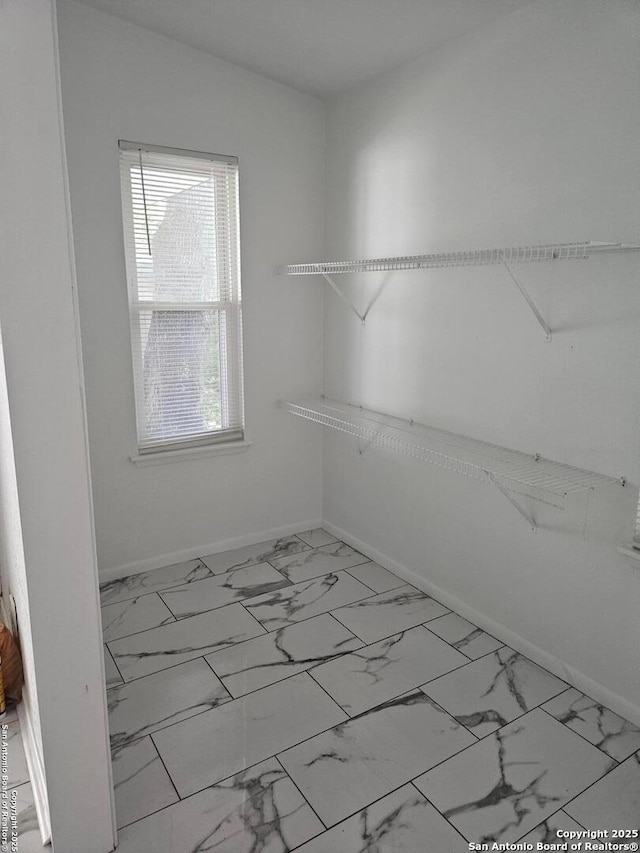 spacious closet featuring marble look tiles