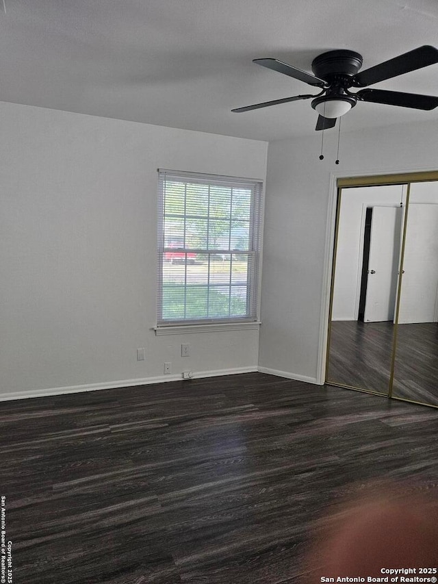 unfurnished bedroom with dark wood finished floors, baseboards, a ceiling fan, and a closet