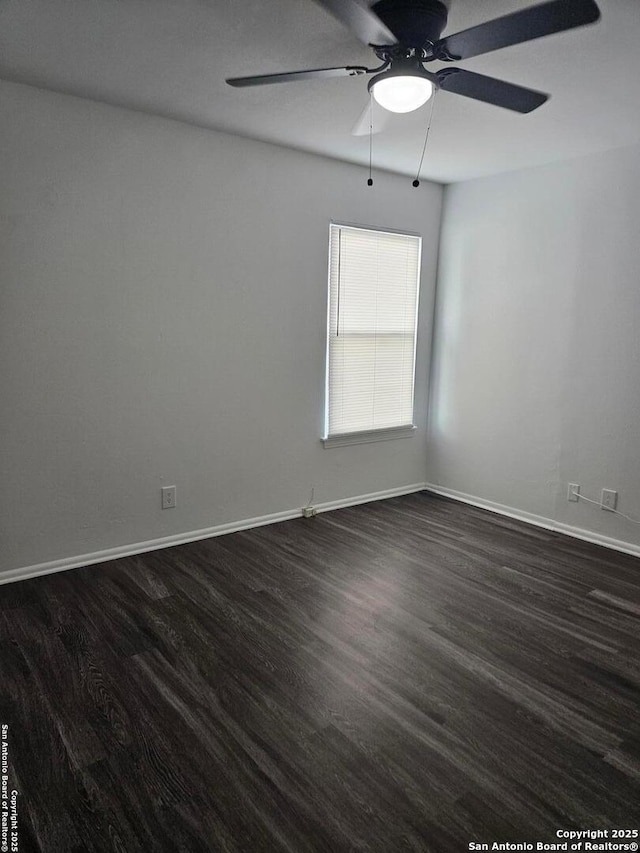 spare room featuring ceiling fan, dark wood finished floors, and baseboards