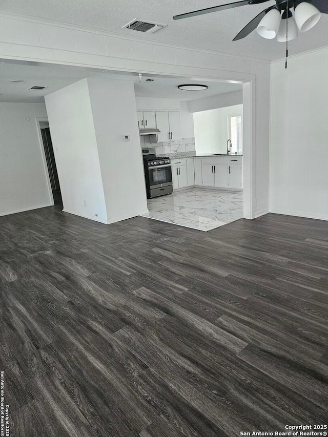 unfurnished living room featuring a ceiling fan, dark wood-style floors, and a sink