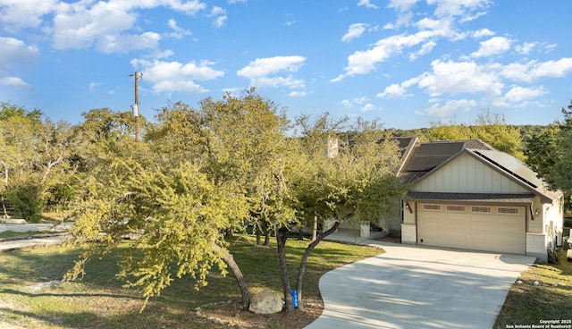 1345 Birch Ln, Fischer, TX 78623 - view of property hidden behind natural elements featuring board and batten siding, concrete driveway, solar panels, and a garage