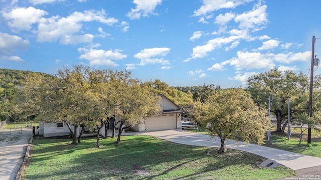 1345 Birch Ln, Fischer, TX 78623 - view of property hidden behind natural elements featuring a front lawn, concrete driveway, and an attached garage
