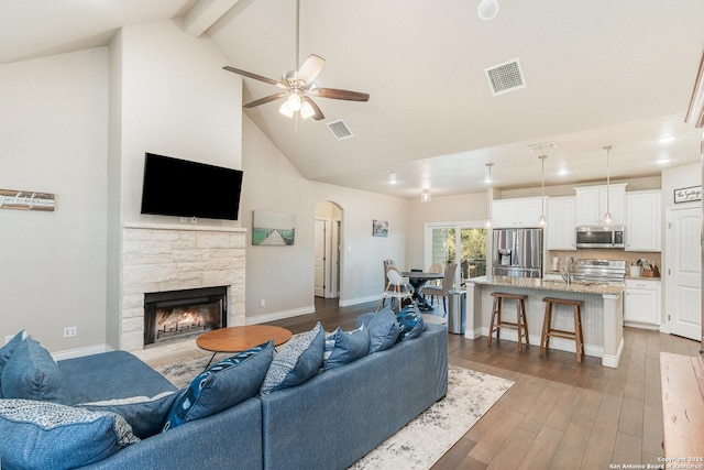 1345 Birch Ln, Fischer, TX 78623 - living area featuring high vaulted ceiling, a stone fireplace, a ceiling fan, wood finished floors, and arched walkways