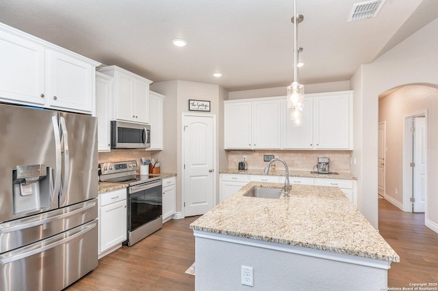 1345 Birch Ln, Fischer, TX 78623 - kitchen with stainless steel appliances, a sink, arched walkways, wood finished floors, and tasteful backsplash