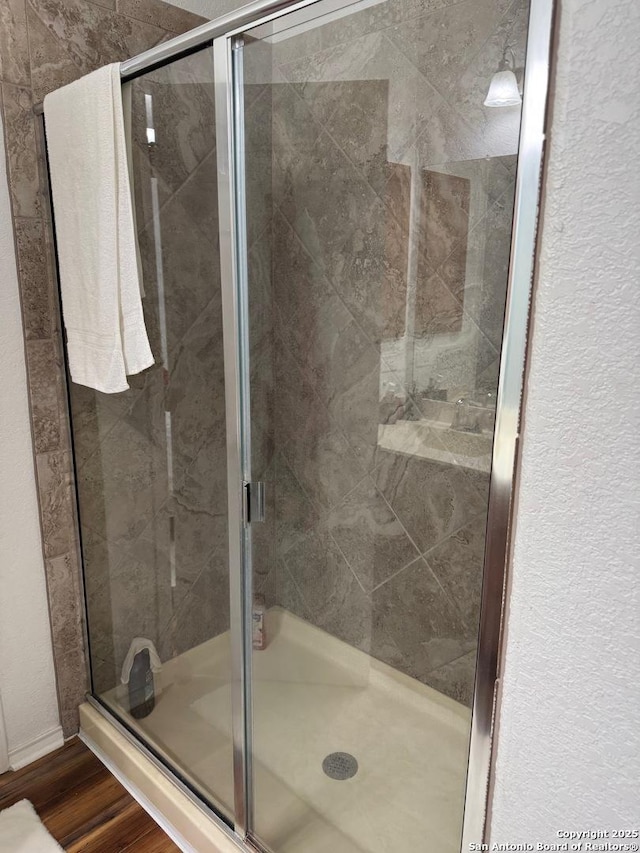 full bath with a shower stall and wood finished floors