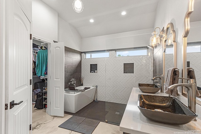 397 County Road 367, Hondo, TX 78861 - bathroom featuring tile walls, marble finish flooring, a freestanding bath, vaulted ceiling, and a spacious closet