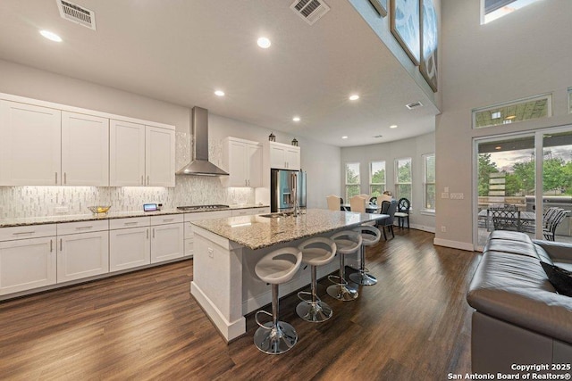 150 Cool Rock, Boerne, TX 78006 - kitchen featuring wall chimney range hood, stainless steel appliances, white cabinets, tasteful backsplash, and a kitchen breakfast bar