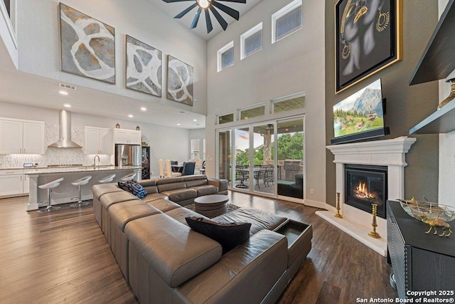 150 Cool Rock, Boerne, TX 78006 - living area with a ceiling fan, dark wood-style floors, a glass covered fireplace, healthy amount of natural light, and a high ceiling