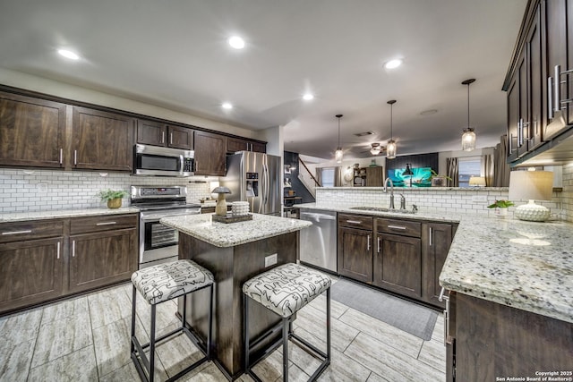 kitchen featuring stainless steel appliances, a sink, a peninsula, backsplash, and recessed lighting