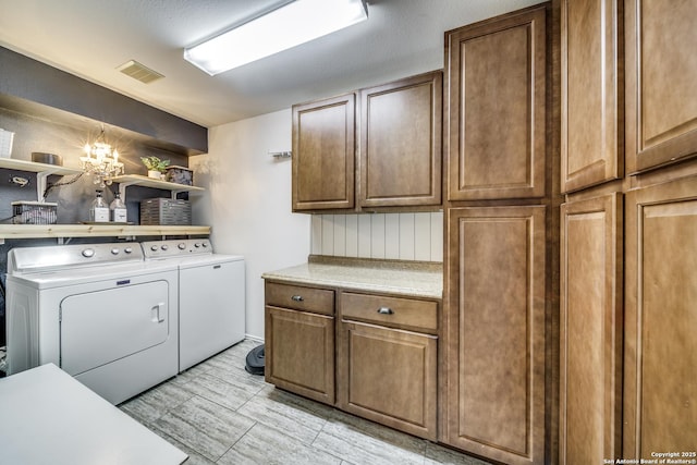 clothes washing area with cabinet space, washing machine and clothes dryer, and a chandelier