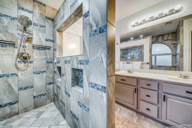 bathroom with a tile shower and double vanity