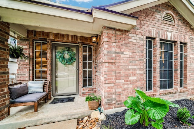 entrance to property featuring brick siding and covered porch