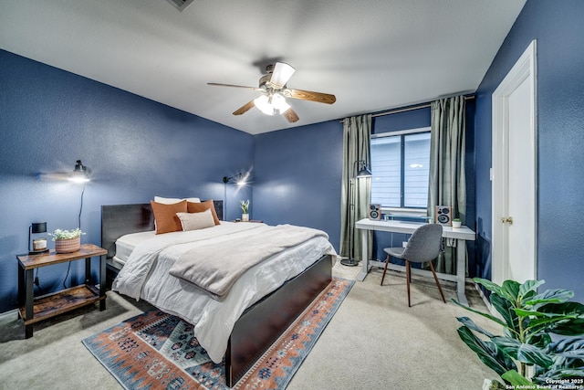 carpeted bedroom with a desk, a textured wall, and ceiling fan