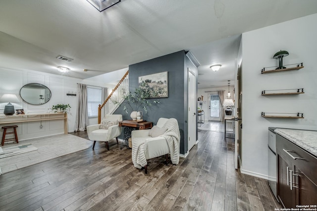 living room with stairs, dark wood-style flooring, and baseboards