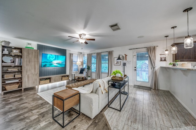 living area featuring a ceiling fan, light wood-type flooring, and baseboards