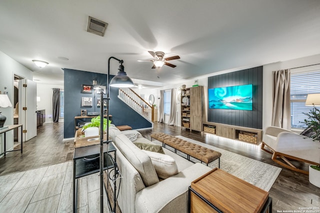 living area with stairs, ceiling fan, wood finished floors, and baseboards