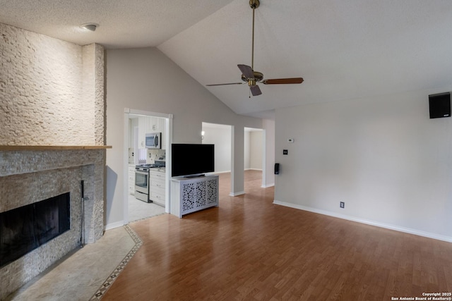 unfurnished living room featuring a ceiling fan, a tiled fireplace, light wood-type flooring, high vaulted ceiling, and baseboards