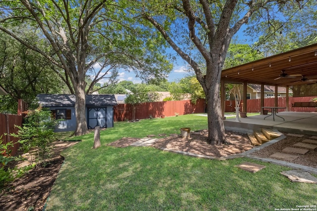 view of yard featuring ceiling fan, a patio area, and an outdoor structure