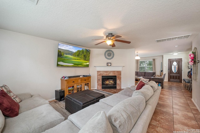 3911 Valencia Peak, San Antonio, TX 78261 - living room with ceiling fan, a textured ceiling, baseboards, a fireplace, and light tile patterned floors