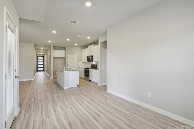 11515 Cottage Pt, San Antonio, TX 78254 - kitchen with stainless steel appliances, a sink, baseboards, white cabinets, and a center island with sink